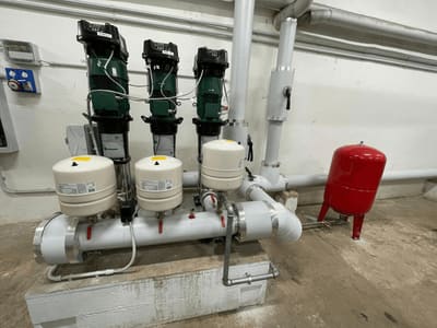Gruppo di pompe con autoclavi e vaso di espansione rosso in un locale tecnico